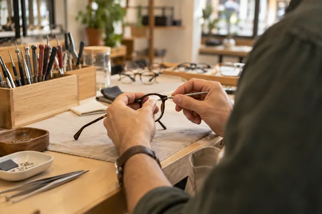 Óptico ajustando una montura de gafas sobre su mesa